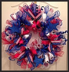 a red, white and blue mesh wreath with stars on the bottom is hanging on a door