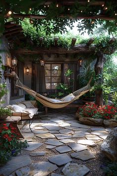 a hammock hanging in the middle of a stone patio with potted plants