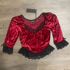 This Velvet Bustier Top Has A Cropped Fit, Lace Trim, Ribbon Tie Details, Puff Shoulders, And Half-Length Sleeves. Fitted Red Top With Lace Trim, Fitted Red Tops With Lace Trim, Gothic Tops With Lace Trim For Fall, Red Fitted Top For Costume Party, Halloween Party Top With Ruffles, Halloween Party Ruffle Top, Red Tops For Fall Costume Party, Red Top For Fall Costume Party, Fitted Red Top For Halloween