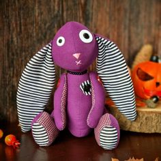 a purple stuffed animal sitting on top of a table next to pumpkins and other decorations