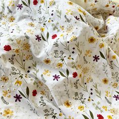 an unmade bed with white and yellow flowers on the sheets, next to a pillow