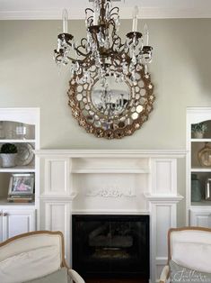 a living room filled with furniture and a chandelier above a fire place in front of a fireplace