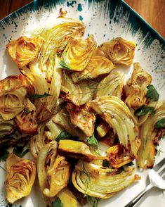 a white plate topped with cooked artichokes on top of a wooden table