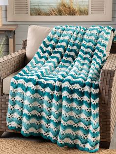 a blue and white blanket sitting on top of a couch next to a chair in front of a window