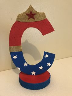 a red, white and blue letter with a star on it's top sitting on a table