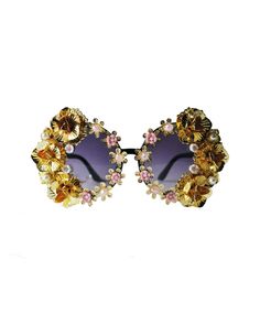 These dramatic gold floral sunglasses will make you feel ultra fabulous- the compliments are guaranteed OFF THE CHARTS! These plastic frames have round shaped dark tinted lenses and feature an all-over hand embellished frame with assorted flower accents. Each pair is one-of-a-kind and as unique as you are. As if it couldn't get anymore fabulous, these sunnies are complete with a removable neck chain strap with pearl embellishment attached at each temple! These super fun sunglasses ship with a cl Chic Round Frame Sunglasses For Party, Chic Metal Sunglasses For Party, Glamorous Gold Party Sunglasses, Glamorous Gold Sunglasses For Party, Gold Mirrored Sunglasses For Party, Gold Metal Sunglasses For Party, Gold Mirrored Lenses Sunglasses For Party, Bohemian Sunglasses For Summer Parties, Glamorous Gold Sunglasses For Summer