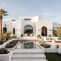 a white house with a pool surrounded by greenery