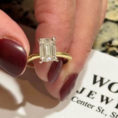 a close up of a person holding a ring with a diamond on it's finger