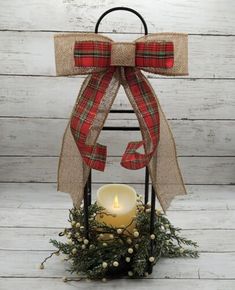 a candle with a bow on it sitting in front of a white wooden wall and wreath