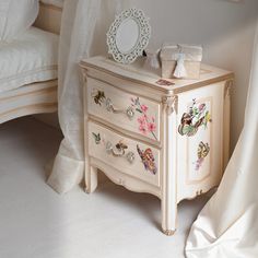 a white dresser sitting next to a bed in a bedroom