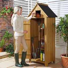 a woman standing next to a potted plant in a wooden shed with gardening tools