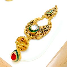 This magnificent choker set, crafted from 22k gold with an antique finish, weighs 69.1 grams. It showcases opulent paisley motifs accented with Kundan stones. The necklace is 14.5 inches long and 1.5 inches wide, featuring a drop length of 0.9 inches, creating a statement of refined elegance. With 1 inch of adjustable links, it ensures a perfect fit, secured by a hook lock. The set includes matching earrings, each 3 inches in length, equipped with screw-back posts for secure wear. This ensemble Traditional Dual-tone Gold Jewelry, Heavy Chandbali Temple Necklace For Formal Occasions, Traditional Gold Hallmarked Kundan Necklace, Traditional Antique Gold-plated Jewelry, Ornate Gold Kundan Chandbalis, Ornate Gold Chandbalis With Kundan, Gold Meenakari Tikka For Ceremonial Occasions, Gold Meenakari Tikka For Ceremonial Use, 22k Gold Bollywood Jewelry For Formal Occasions