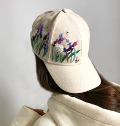 a woman wearing a white baseball cap with flowers embroidered on the front and back side