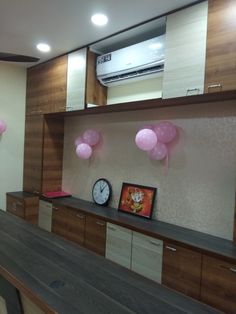 balloons are floating in the air near a clock on a shelf with other decor items