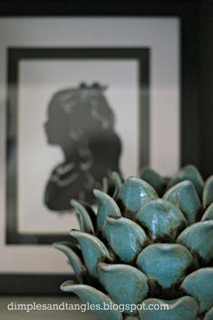 a pineapple sitting on top of a table in front of a framed photo with a black and white background