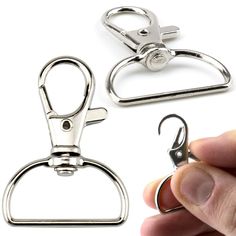 a hand holding a pair of scissors next to another set of metal clips on a white background