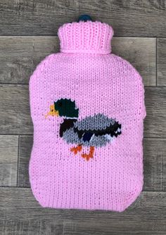 a pink knitted hot water bottle with an image of a bird on the side