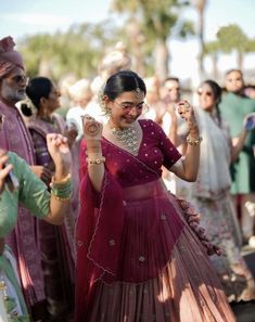 a woman in a red dress is dancing with other people behind her and one person holding something up to the side