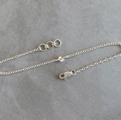 two silver chains on a gray surface