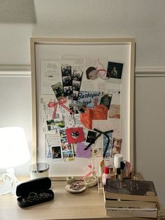 a wooden desk topped with lots of clutter next to a framed photo on the wall