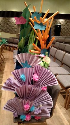 there are many different colored paper fans on the table in front of rows of chairs