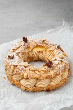 a cake covered in powdered sugar and nuts on top of wax paper with crumbs