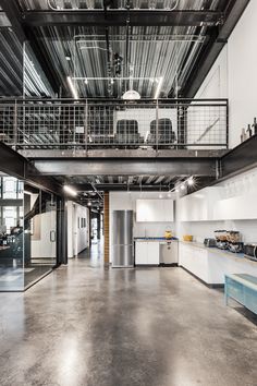 an industrial kitchen with white cabinets and stainless steel stairs leading up to the second floor