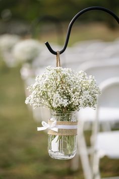 a mason jar filled with baby's breath flowers hanging from a black metal hook