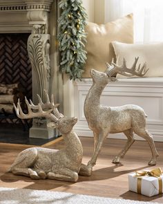 two deer statues sitting on the floor next to a christmas tree