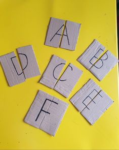 several pieces of paper cut into letters on a yellow surface with the word abc and f spelled out