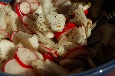 a bowl filled with sliced up radishes and seasoning next to a fork