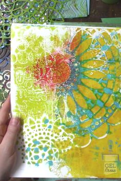 someone is holding up an art journal that has been decorated with bright colors and designs