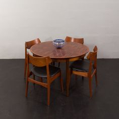 a wooden table with chairs around it and a bowl on the table in front of it