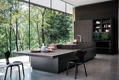 a modern kitchen with an island counter and black chairs in front of the open window