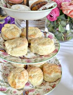 three tiered plates with biscuits on them and pink flowers in vases behind it