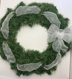 a wreath made out of grass with white ribbons