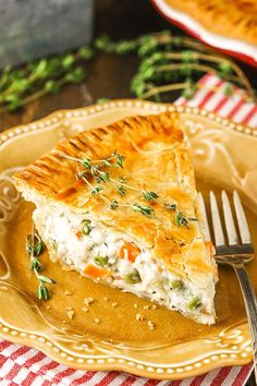 a slice of chicken pot pie on a yellow plate with a fork and red checkered table cloth