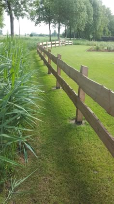 a wooden fence in the middle of a grassy field