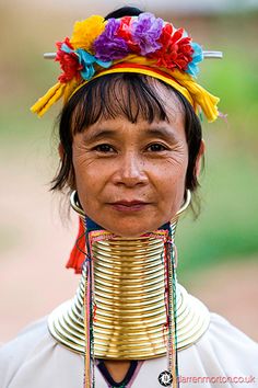 a woman wearing a colorful headdress and metal neck piece with flowers in her hair