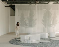 a woman is standing in front of an art installation with trees on the wall behind her