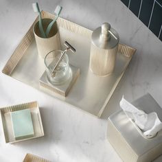 three square trays with soap dispensers and napkins on them sitting on a marble countertop