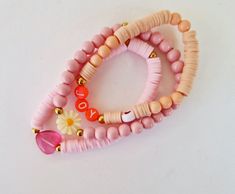 This pretty in pink bracelet stack is perfect for adding some fun and sparkle to your bracelets stack. This stack consists of three bracelets as shown in the images.  Please also note that these bracelets are not for children.  Bracelets will be made in the standard adult size (7 inches (17.8 cm).  - Acrylic letter beads (orange with white and a heart bead). - Stainless steel gold beads used as accents. - Pink glass crystal heart. - White mother of pearl daisy. - Pink heishi beads. - Pink glass Trendy Stacked Pink Beaded Bracelets, Trendy Pink Stacked Beaded Bracelets, Trendy Stacked Pink Bracelets, Trendy Pink Stacked Bracelets, Pink Stretch Bracelet With Round Beads For Everyday, Pink Round Beads Stretch Bracelet For Everyday, Pink Stacked Stretch Bracelet As Gift, Adjustable Stackable Pink Stretch Bracelet, Adjustable Pink Stackable Friendship Bracelets