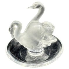 a glass swan figurine sitting on top of a black base with a white background