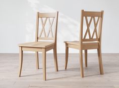 two wooden chairs sitting side by side on top of a hard wood floor next to each other