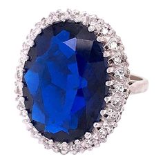 A very fine gold and multi-gemstone cocktail ring.  In 14k white gold.   Set with a large deep blue oval-cut topaz surrounded by a halo of 24 small round-cut diamonds.  Simply an eye-catching ring that is fun to wear and makes you look!  Marks: Marked to the shank 14k for gold fineness.  Dimensions: Length: ca. 22mm Width: ca. 20mm  Ring Size: ca. 6 3/4  Gemstone Dimensions: Topaz: ca. 18mm x 13mm x 5.5mm  Items purchased from this dealer must delight you. Topaz Cocktail Ring, White Gold Set, Gold Cocktail Ring, Golden Ring, Gold Cocktail, Diamond Cocktail Rings, Large Jewelry, London Blue Topaz, Topaz Gemstone