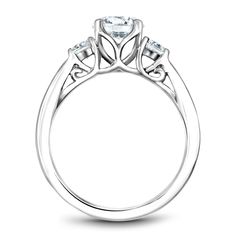 a white gold engagement ring with three stones on the shoulders and an intricate design around the band