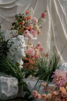 flowers and statues are arranged in front of a white sheet