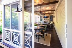 an open porch with chairs, table and television on the back wall in front of it