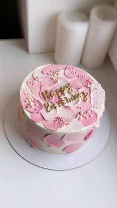 a pink and white cake sitting on top of a table