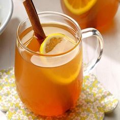 two mugs filled with tea and cinnamon sitting on a table